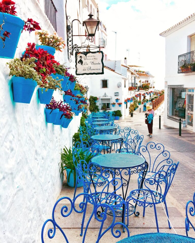 Picturesque outdoor café with vibrant blue chairs in Mijas, showcasing Andalusian charm.