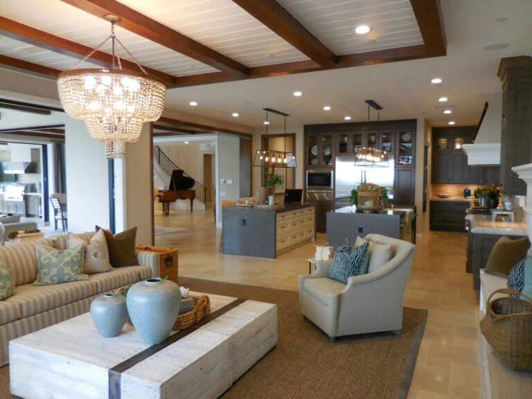 Spacious living room with elegant decor and an open kitchen area, featuring a chandelier and comfortable furnishings.