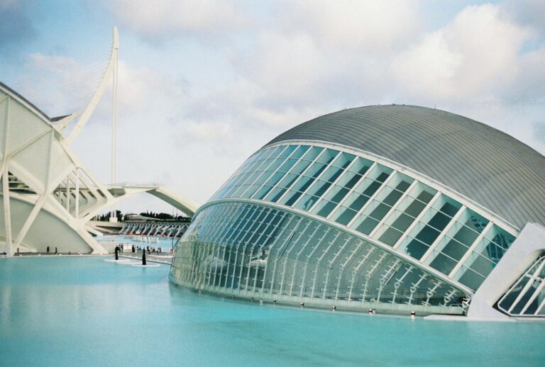 Modern architecture of the Hemisferic building in Valencia, Spain, reflecting in a tranquil pond.